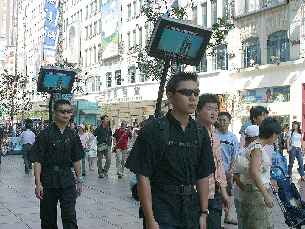 People walking with computer screens on their back