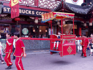 Boy in sedan chair in front of Starbucks in Shanghai